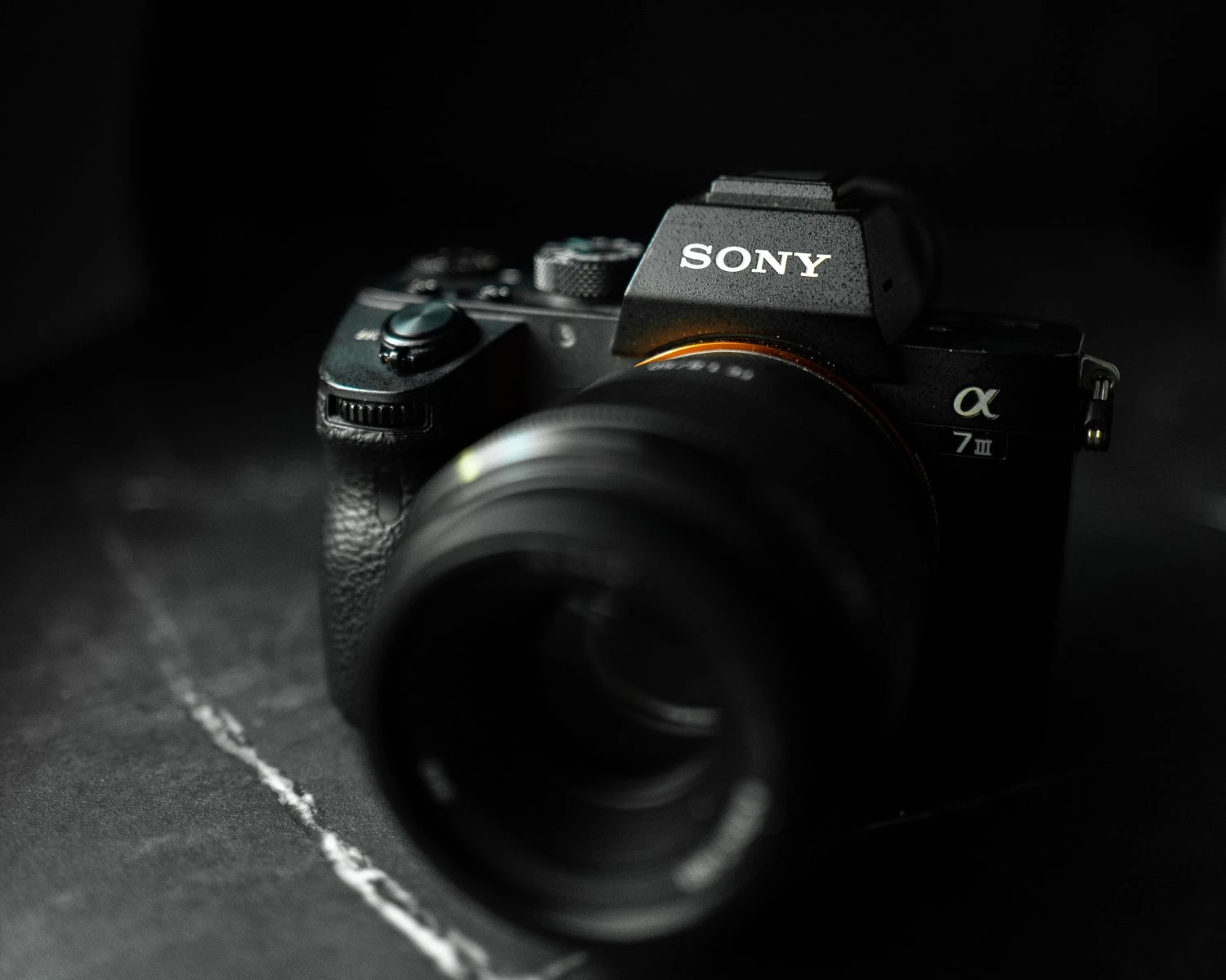 The Sony A7 III camera on a dark surface.