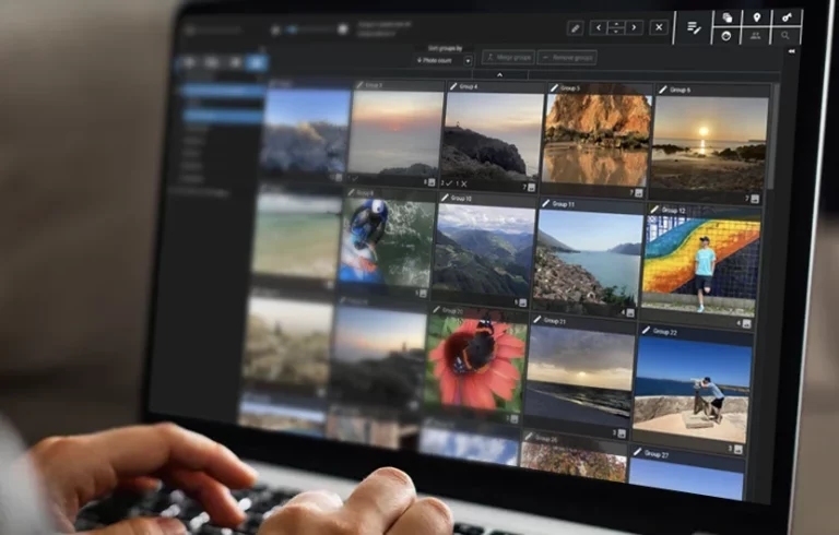 Person tippt auf Laptop, der eine Fotoverwaltungssoftware mit Bildern anzeigt