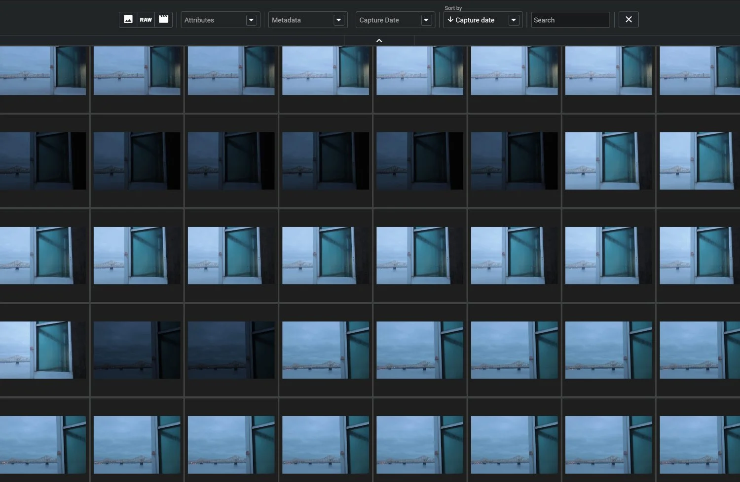 Grid of image thumbnails in a photo-management program showing a window and a distant bridge.