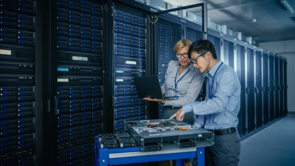 Zwei IT-Fachkräfte arbeiten an Serverhardware im modernen Rechenzentrum