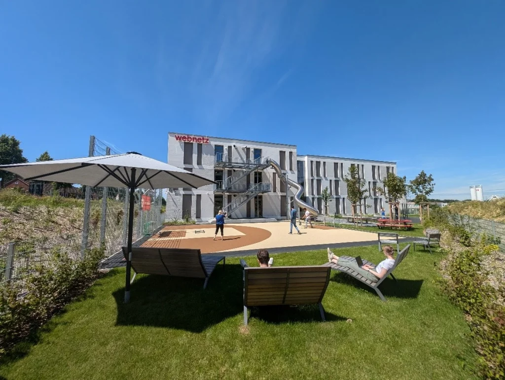 Außenansicht des Webnetz Campus in Lüneburg mit Rutsche und Fußballfeld
